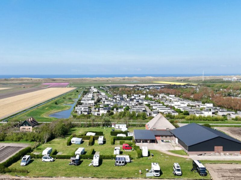 Luchtfoto van Hoeve Voorwaarts: caravans en campers in het groen, met de Noordzee en bloembollenvelden op de achtergrond