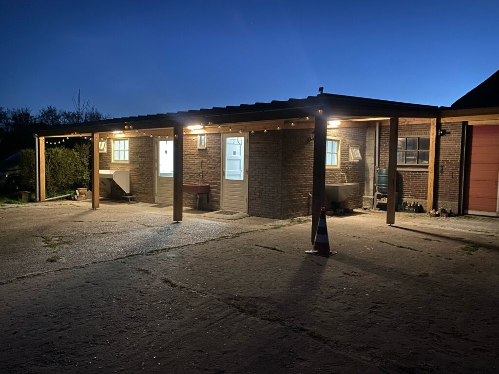 Het sanitairgebouw van Hoeve Voorwaarts in de avond, sfeervol verlicht met kerstlampjes